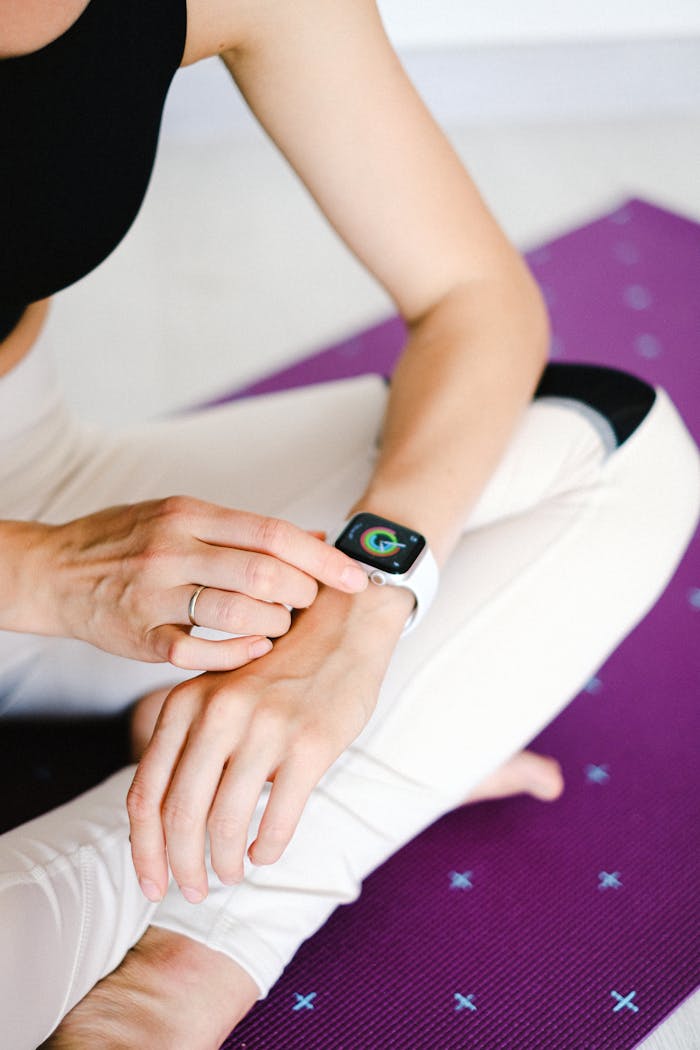 why-choose-us Close-up of woman adjusting smartwatch while sitting on a yoga mat, focusing on fitness and technology.