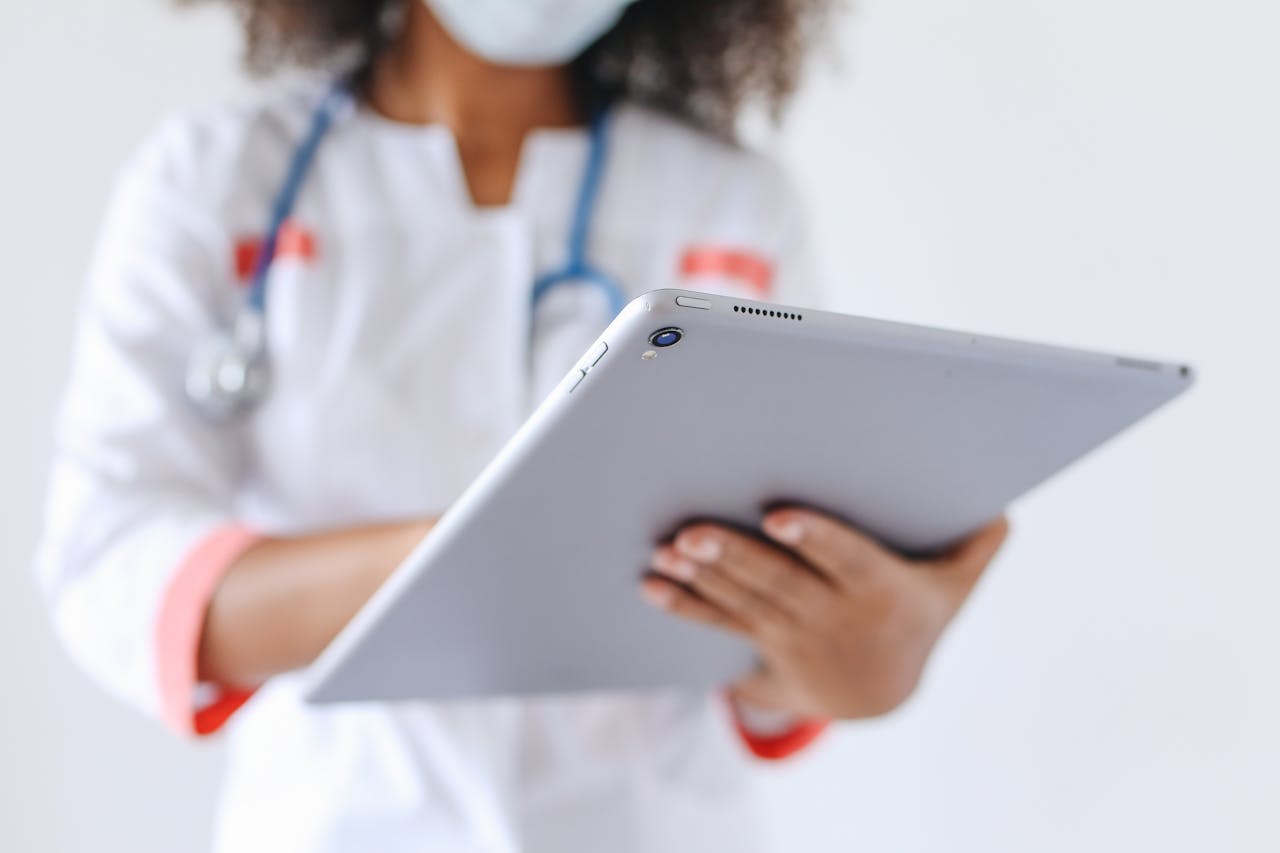 about-us Close-up of a doctor wearing a mask using a tablet for healthcare management.